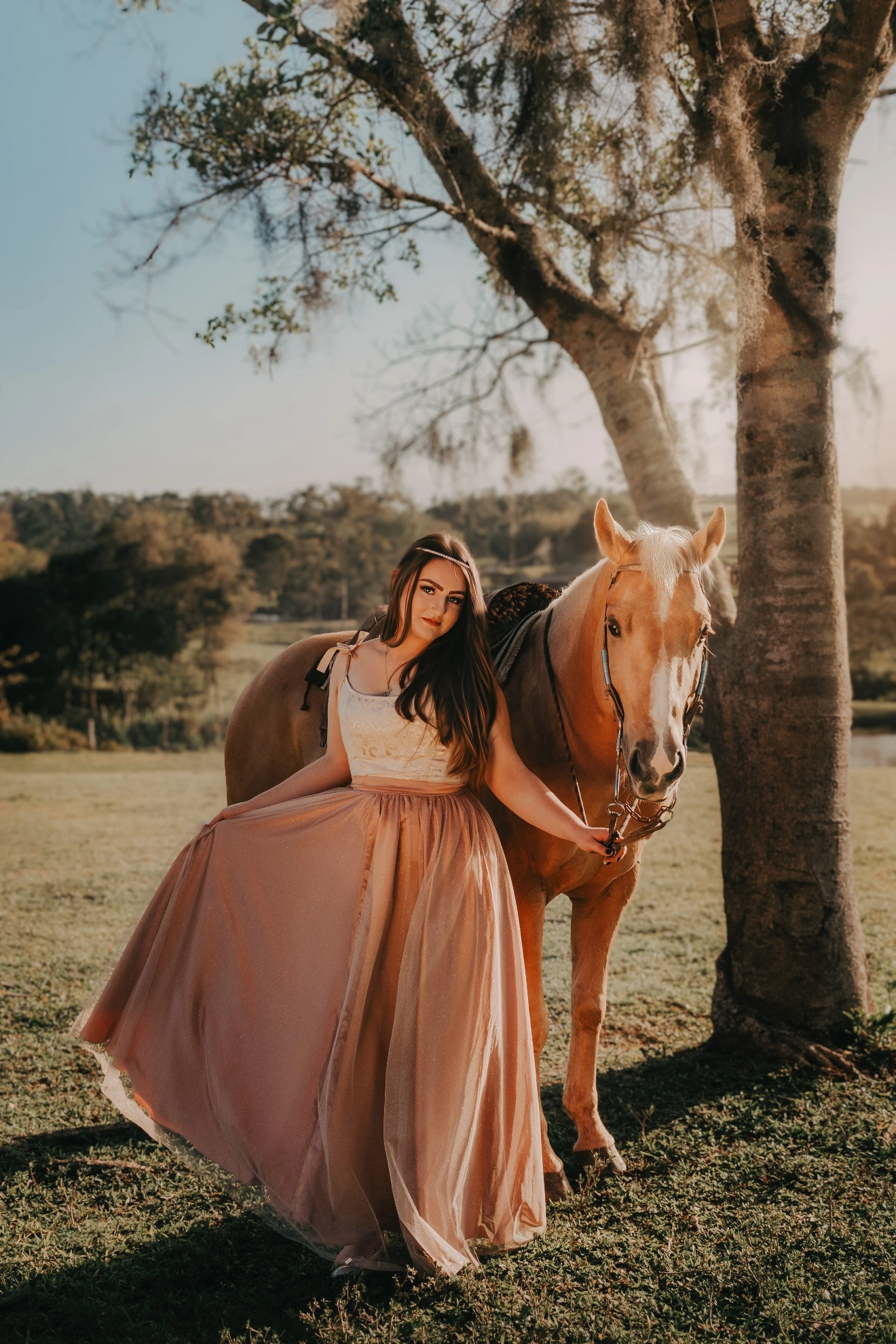 Mulher ao lado de um cavalo sob uma árvore